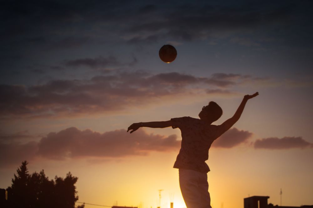 man hitting volleyball at sunset